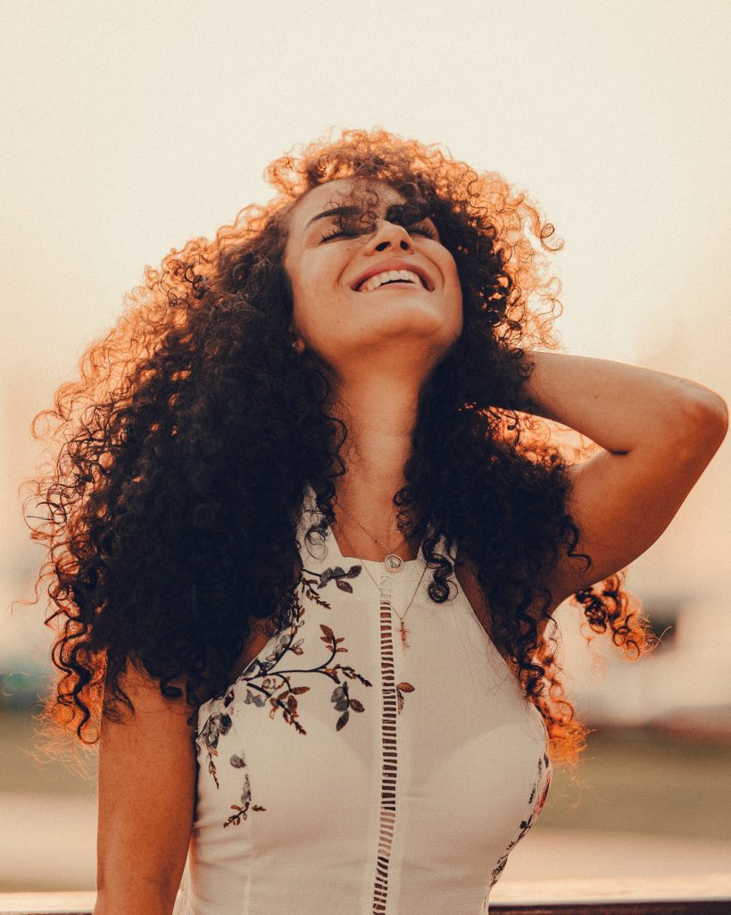 Woman With Curly Hair Smiling Up At The Sky