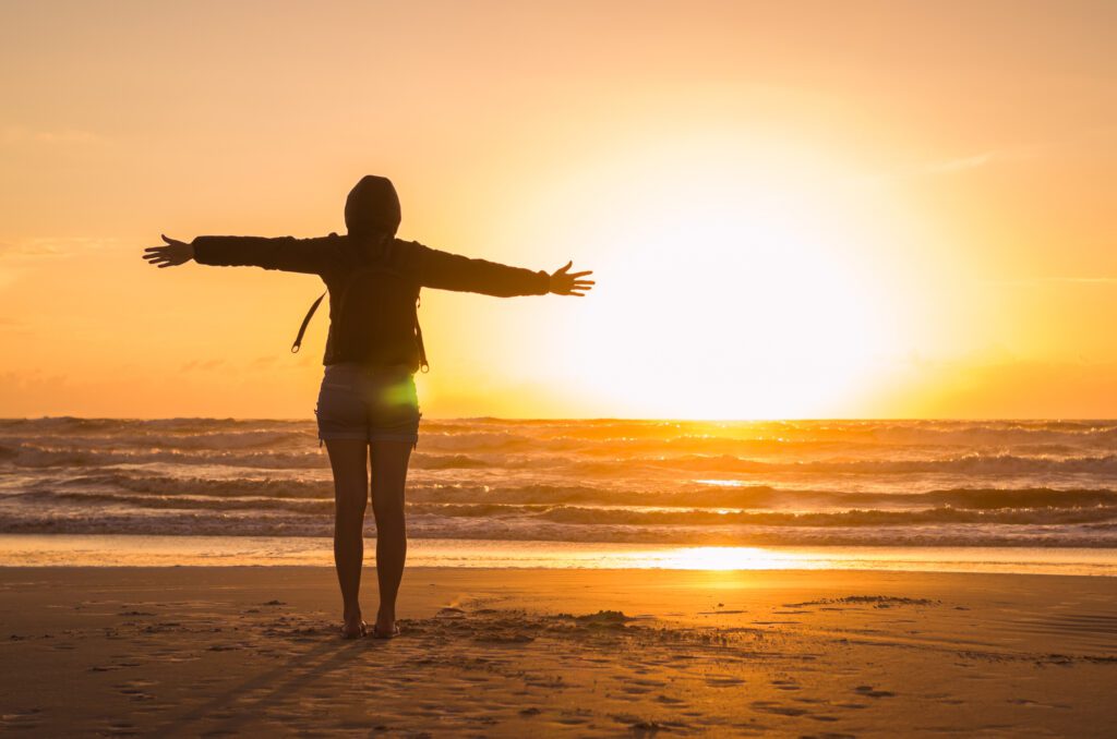 Woman looking at the horizon, beach at sunset