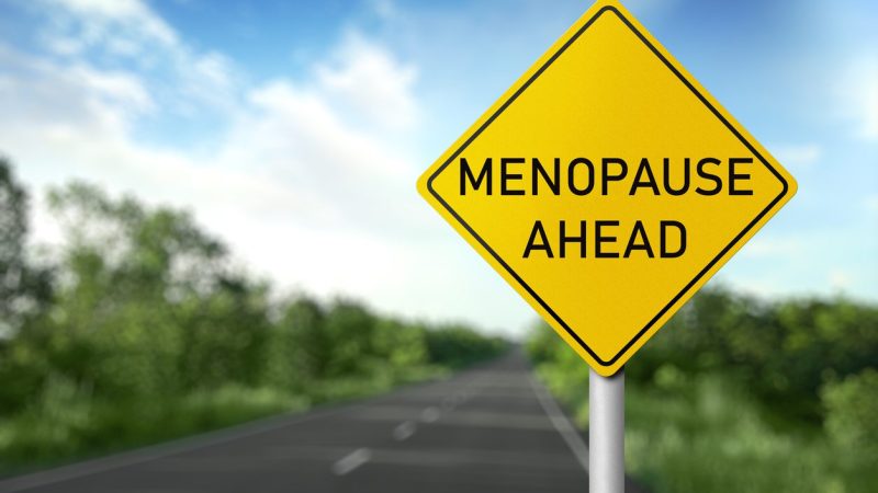 Concept of impending climacteric. Sign MENOPAUSE AHEAD near asphalt road outdoors