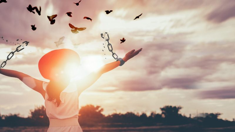 The woman is breaking the chains and setting the birds free, enjoying the nature at sunrise. concept of freedom