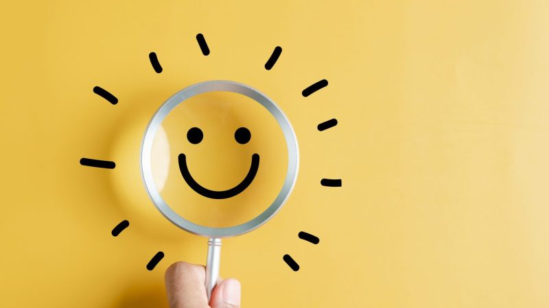 Magnifier focus to smile face emoticon with light bulb smart idea, creativity and solution concept.