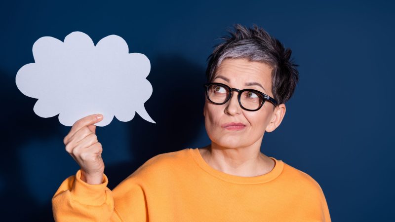 Photo of lovely pensioner lady look skeptical thinking paper cloud dressed stylish yellow garment isolated on dark blue color background.