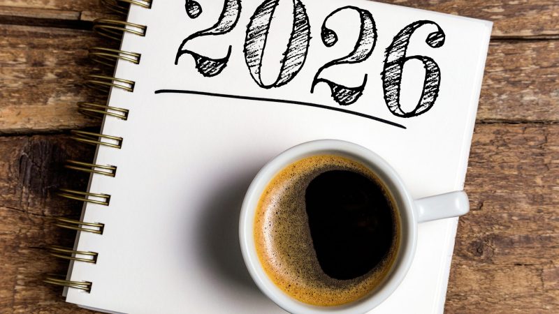 New year resolutions 2026 on desk. 2026 resolutions list with notebook, coffee cup on table. Goals, resolutions, plan, action, checklist concept. New Year 2026 template, copy space