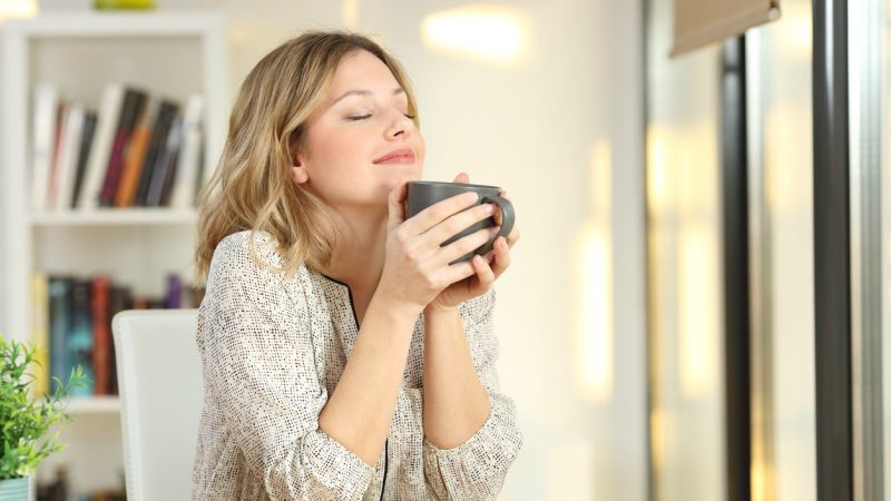 Portrait of a woman breathing and holding a coffee mug at home