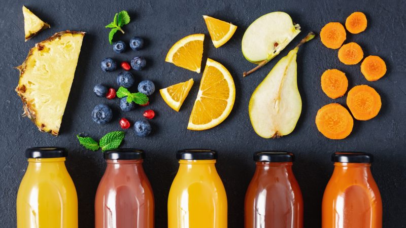 Flat lay various fresh juices from fruit, berries and vegetables in bottles on dark background, top view. Healthy eating concept