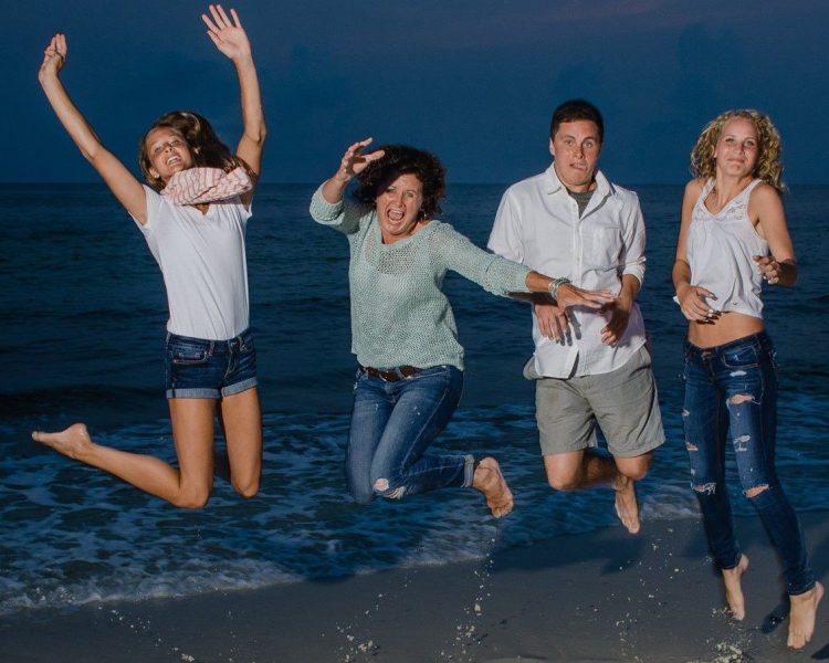 Family Of Four Jumping At The Beach