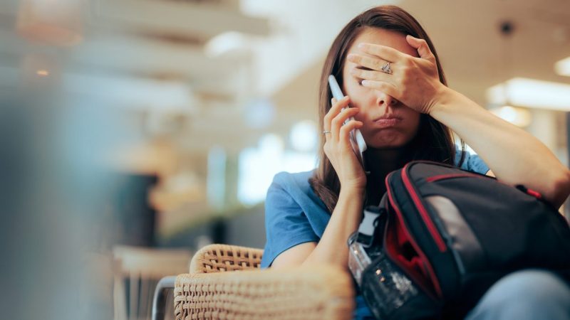 Stressed traveler speaking on her cellphone feeling overwhelmed